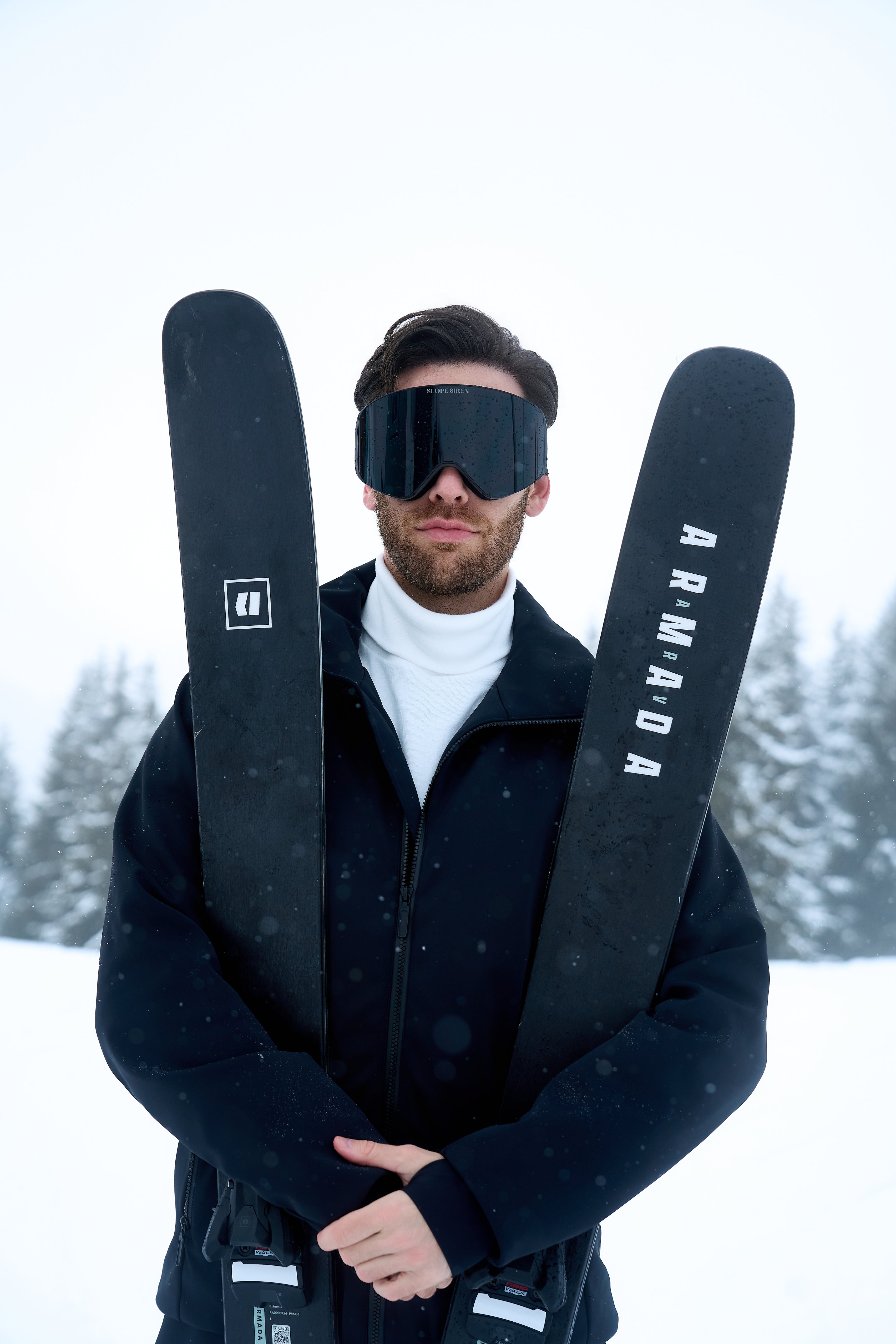 Man wearing Jack ski goggles holding skis in the snow